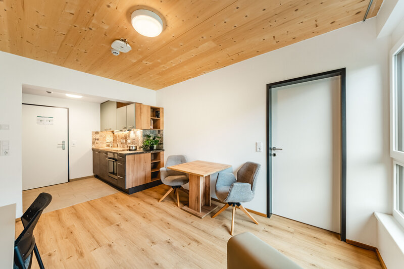 Eine moderne Küche und Essbereich mit Holzböden, Holzdecke und weißen Wänden.