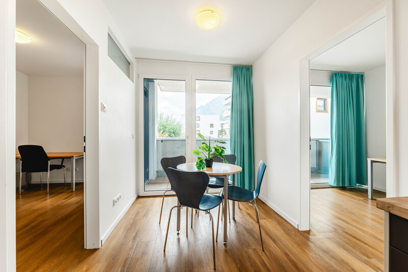 In der Mitte befindet sich ein gut beleuchteter Raum mit einem Tisch und Stühlen. Links und rechts befindet sich jeweils ein Zimmer.