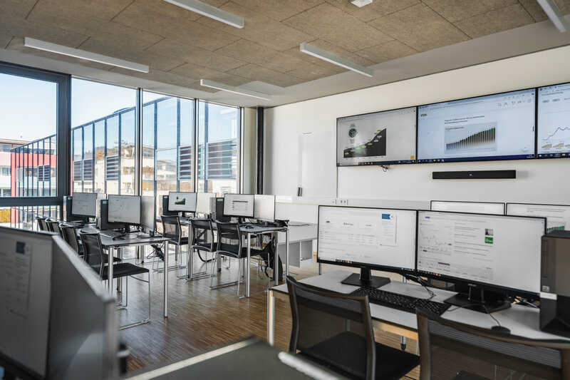 Heller Seminarraum des Finance Lab der HOK mit Computerplätzen und Präsentationsmonitoren.