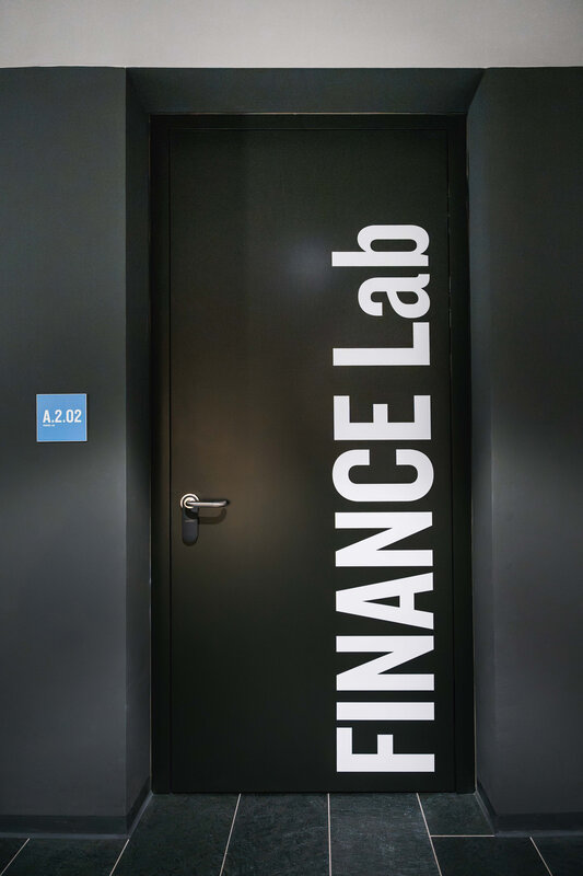 Eingangstür zum Finance Lab der HOK mit großem weißen Schriftzug und Raumbeschilderung.