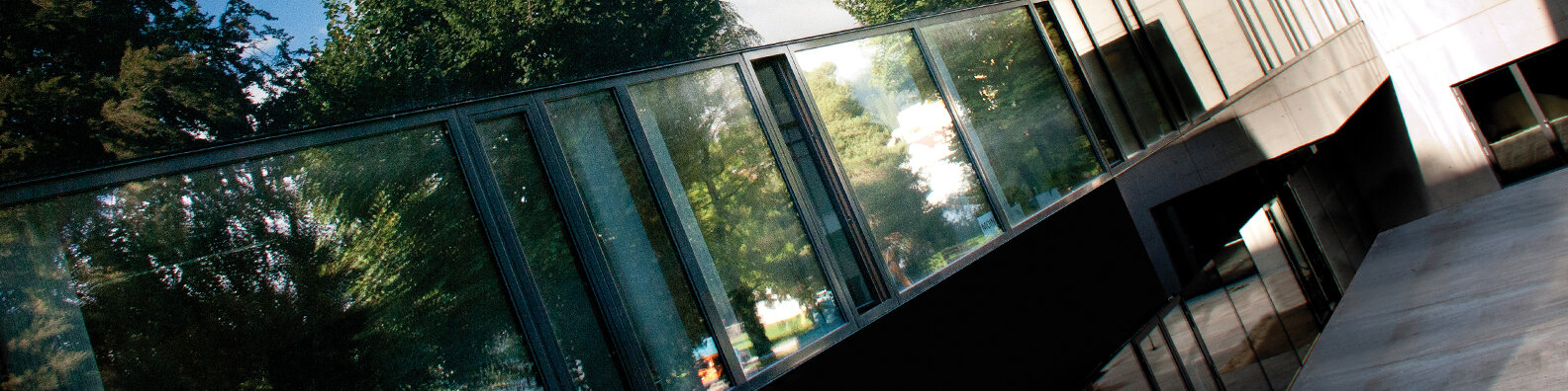 Moderne Glasfassade der HOK mit Spiegelung der umliegenden Bäume | © HOK