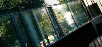 Moderne Glasfassade der HOK mit Spiegelung der umliegenden Bäume