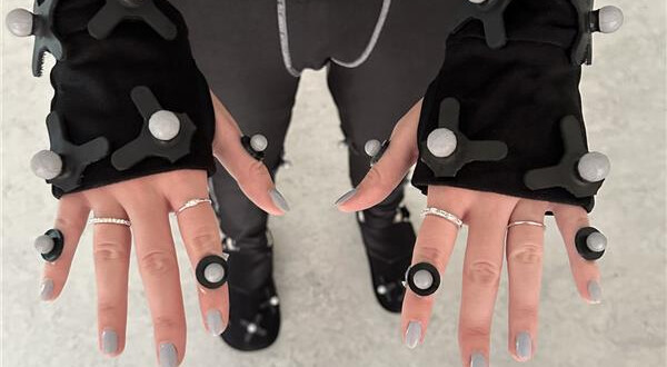 Detailaufnahme der Hände einer Person im Motion-Capture-Anzug mit Reflektionsmarkern und Fingertrackern im MoCap-Lab der HOK