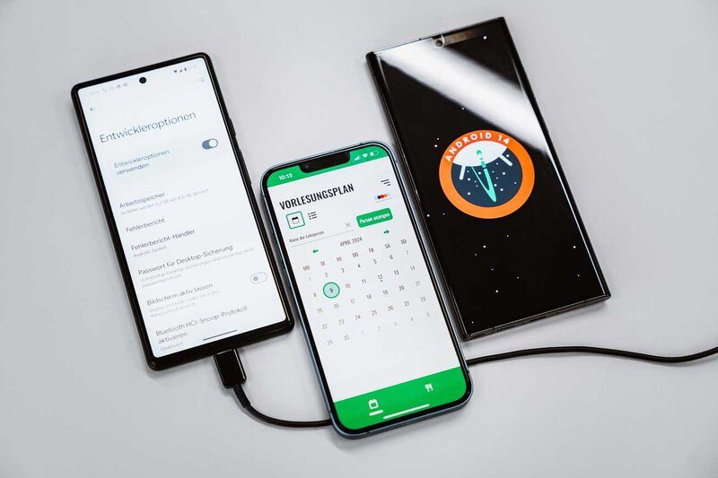 Drei Smartphones mit Android-Entwickleroptionen, Stundenplan-App und Android-14-Logo im Web Lab der HOK.