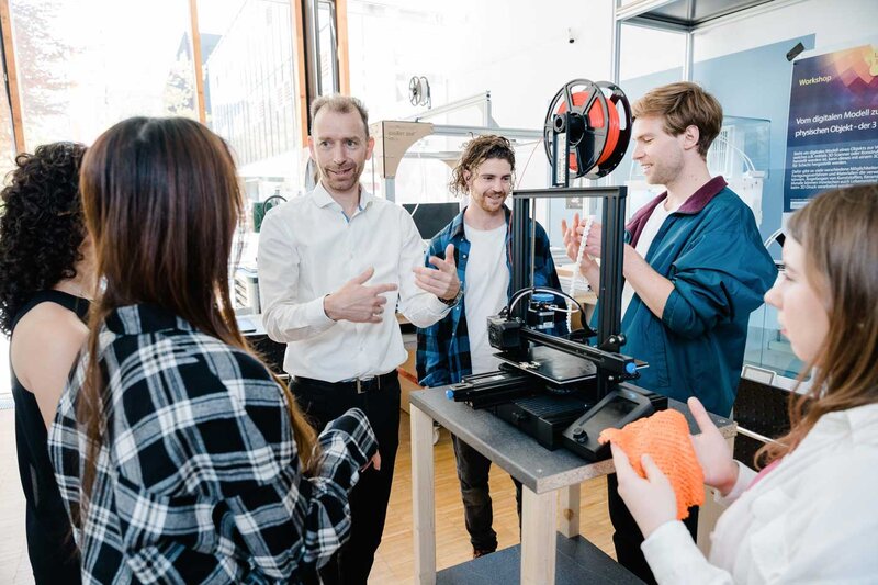 Dozent erklärt einer Gruppe von Studierenden im Makers Lab der HOK die Funktionsweise eines 3D-Druckers und den Ablauf des Druckprozesses.