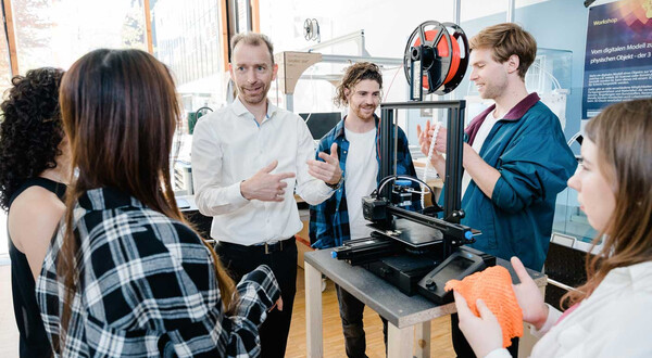 Dozent erklärt einer Gruppe von Studierenden im Makers Lab der HOK die Funktionsweise eines 3D-Druckers und den Ablauf des Druckprozesses.