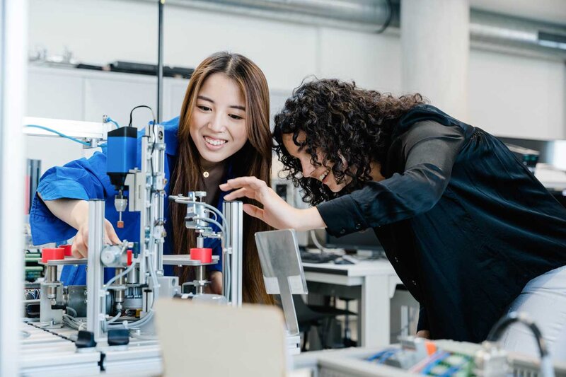 Zwei Studierende arbeiten gemeinsam an einer automatisierten Fertigungsanlage im Automation Lab der HOK.