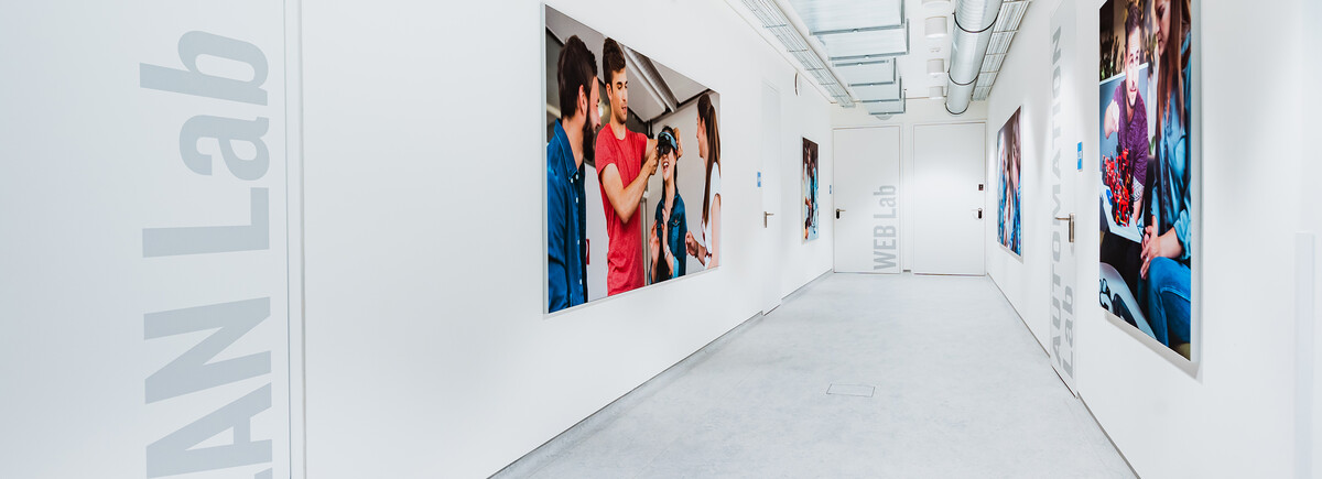 Flur mit Wandfotos und Laborbeschriftungen an der HOK