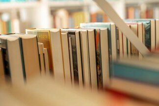 Nahaufnahme von Büchern im Lesesaal der kubi unscharf im Vordergrund und Hintergrund, Fokus auf mittlere Buchrücken