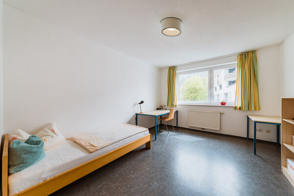 Ein schönes Zimmer mit einem Bett, zwei Schreibtischen und einem Doppelfenster. | © HOK