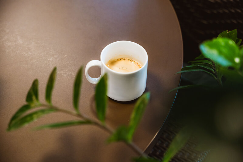 Espressotasse auf rundem Tisch, umrahmt von grünen Pflanzen