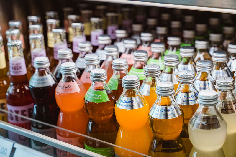 Sortiertes Getränkeregal mit bunten Limonaden und Säften in Glasflaschen