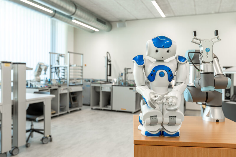 Humanoider Roboter und kollaborativer Roboterarm stehen im Automation Lab der HOK.