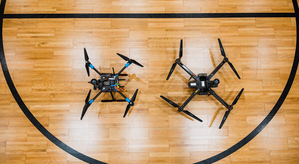Zwei Forschungsdrohnen liegen nebeneinander auf dem Hallenboden des Drone Labs der HOK.