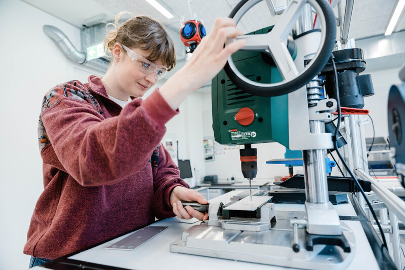 Studentin im Lean Lab der HOK arbeitet mit einer Standbohrmaschine und erlernt praxisnah Methoden des Lean Managements.