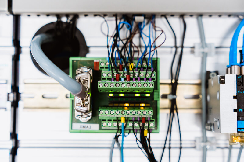 Nahaufnahme eines elektropneumatischen Systems mit Sensoren, Ventilen und Steuerleitungen.