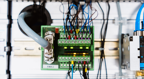 Nahaufnahme eines elektropneumatischen Systems mit Sensoren, Ventilen und Steuerleitungen.
