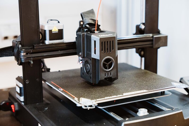 3D-Drucker im Makers Lab der HOK beim Aufbau eines Objekts, Nahaufnahme des Druckkopfs mit Filamentzufuhr.