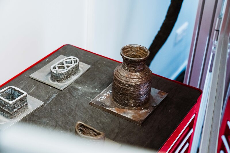 Verschiedene 3D-gedruckte Metallobjekte wie Gefäße und Gitterstrukturen auf einem Arbeitstisch im Makers Lab der HOK.