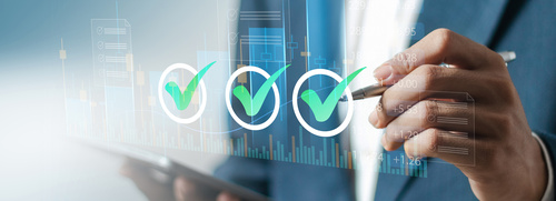 Person in Anzug markiert digitale Häkchen auf einem transparenten Display – steht für Zielerreichung, Qualitätsmanagement und erfolgreiche Projektumsetzung. | © AdobeStock.Pakin