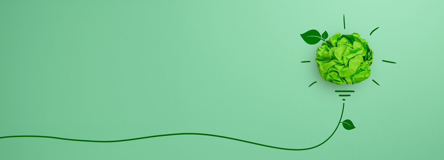 Grüne Glühbirne aus Papier mit Blattelementen auf grünem Hintergrund – Sinnbild für nachhaltige Innovation und kreative Energiekonzepte.