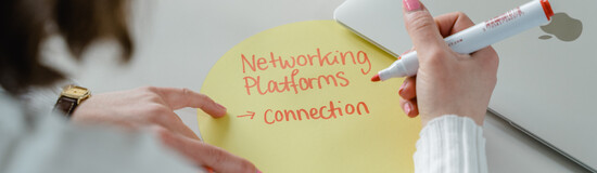 Hand schreibt den Begriff „Networking Platforms – Connection“ auf eine runde Karte – Symbol für Austausch, Kooperation und digitale Netzwerke.
