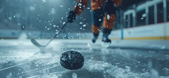 Nahaufnahme eines Eishockey-Pucks auf dem Eis, im Hintergrund ein Spieler in Bewegung – Dynamik, Präzision und Teamgeist im Eishockey.