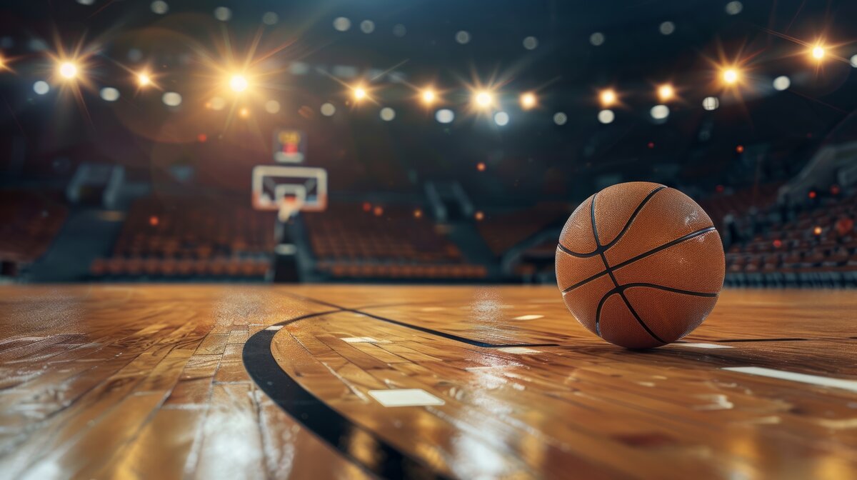 Basketball auf einem beleuchteten Spielfeld in einer Halle – Symbol für Teamgeist, Bewegung und sportliche Dynamik.