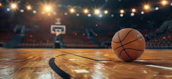 Basketball auf einem beleuchteten Spielfeld in einer Halle – Symbol für Teamgeist, Bewegung und sportliche Dynamik.