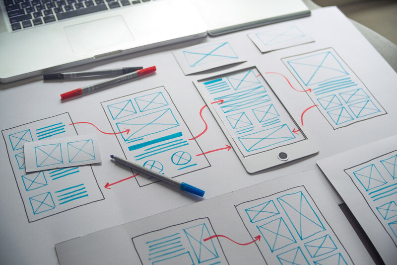 Skizzen eines digitalen Interface-Designs mit Pfeilen und Notizen, Symbol für Konzeption und Entwicklung digitaler Anwendungen, Datenlösungen und Webprojekte.