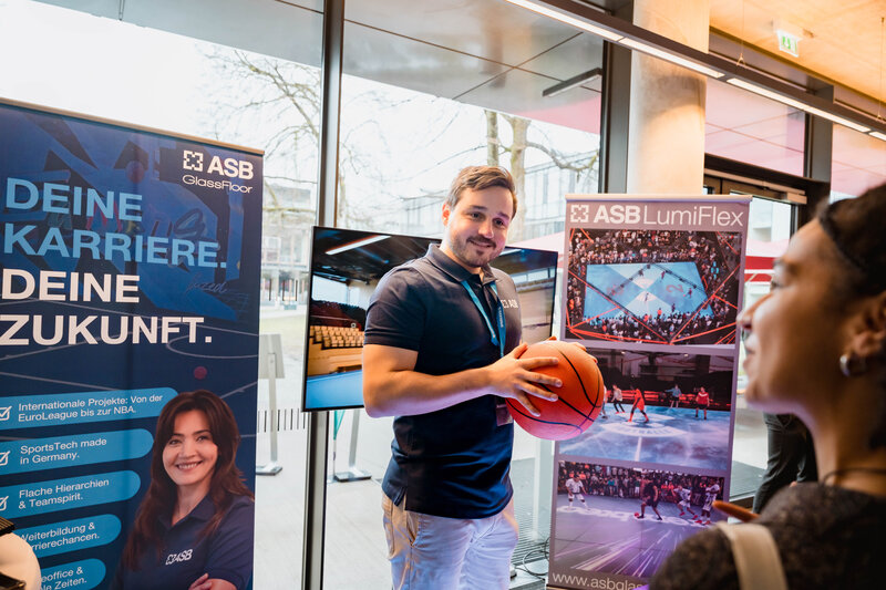 Fabian Bär am Stand von ASB GlassFloor im Gespräch mit Besucher:innen der Meet & Match. 