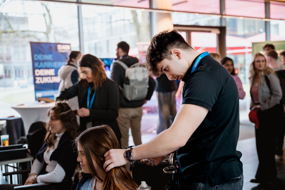 Ein Friseur stylt eine Besucherin der Meet & Match. 