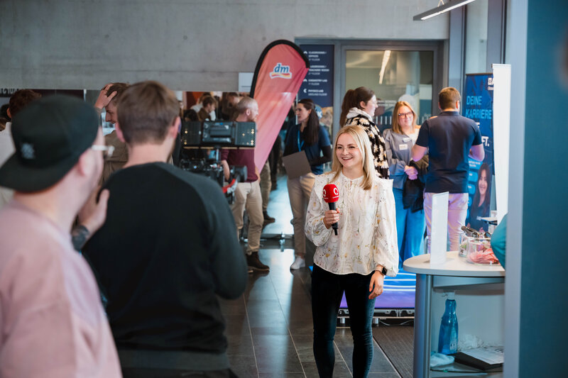 Frau mit Mikrofon spricht auf der Karrieremesse Meet & Match in eine Fernsehkamera
