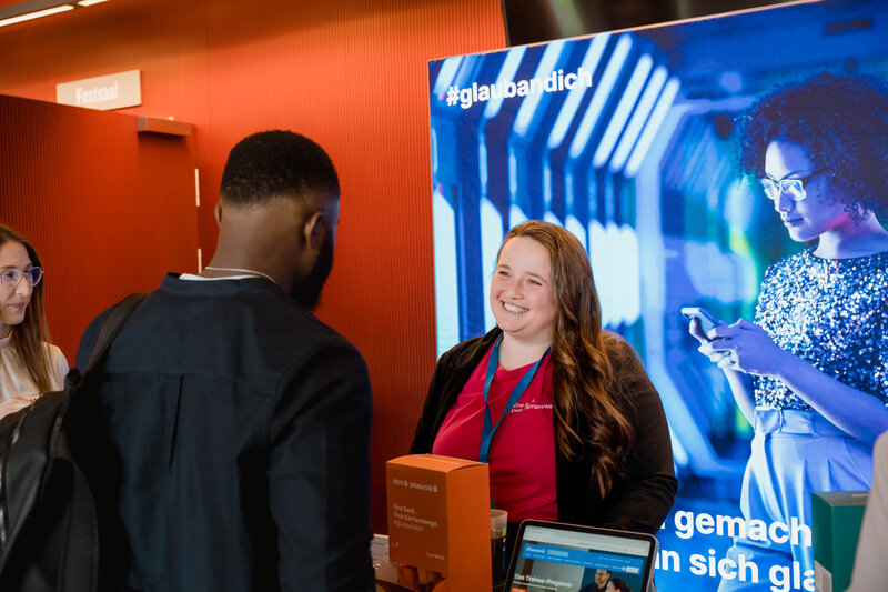 Eine Mitarbeiterin der Sparkasse im Gespräch mit einem Interessenten der Karrieremesse Meet & Match 2025