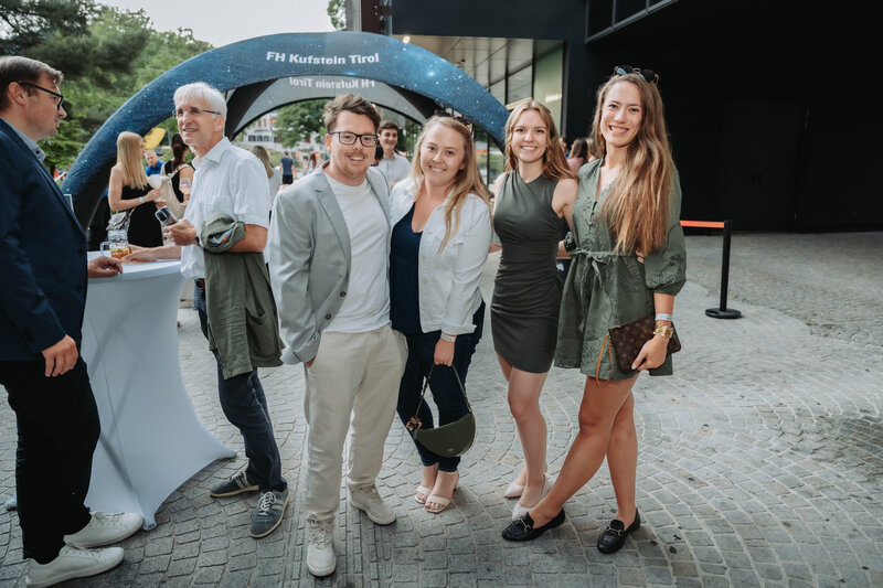 Teilnehmer:innen stellen sich für ein schnelles Foto vor der Homecoming-Kulisse auf.