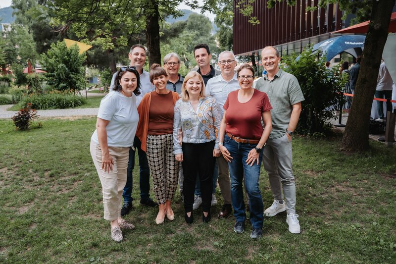 Mehrere Gäste stellen sich lächelnd in Zweierreihen für das Foto auf.