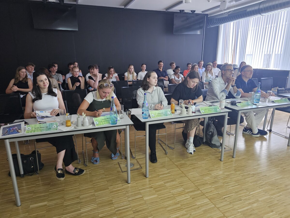 Jury sitzt in vorderster Reihe nebeneinander am Tisch an der HOK.