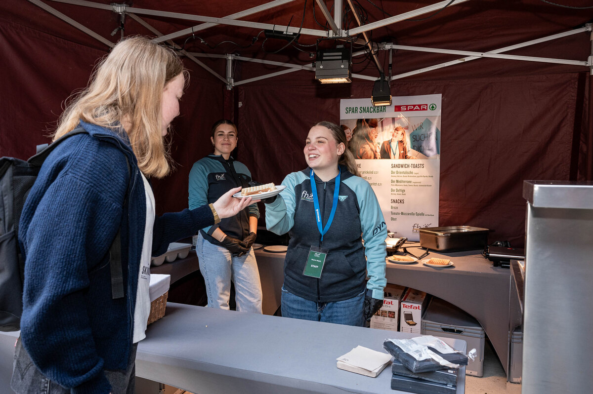 Besucher:innen stehen beim Essensstand und tauschen sich auf der Karrieremesse Meet & Match aus.