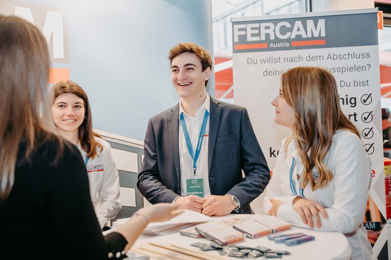 Vier junge Erwachsene stehen an einem Messestand von FERCAM Austria und unterhalten sich 