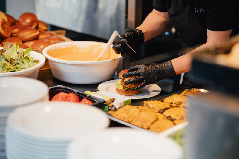 Auf dem Bild ist zu sehen, wie ein Mitarbeiter gerade einen Burger auf dem Homecoming-Event vorbereitet.