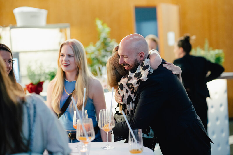 Zu sehen sind fünf Personen, die sich auf dem Homecoming-Event wieder treffen. Sie freuen sich sehr, sich wiederzusehen.