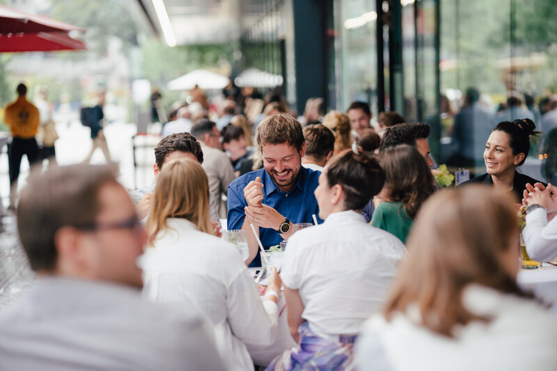 Eine große Gruppe von Personen unterhält sich und lacht beim Homecoming-Event im Außenbereich.