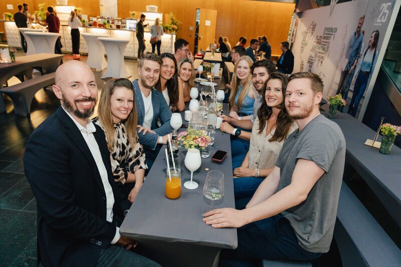 Eine Gruppe von Personen sitzt am Tisch und lächelt.