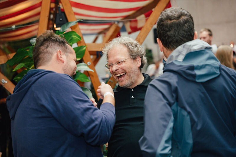 Zu sehen sind drei Personen, die sich auf dem Homecoming-Event wieder treffen. Sie freuen sich sehr, sich wiederzusehen.