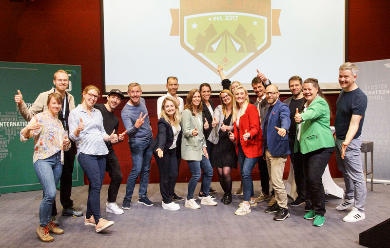 Zu sehen ist das Jurorenteam des INNoCamp. Sie stehen gemeinsam auf einer Bühne. Im Hintergrund befindet sich eine Leinwand mit dem INNoCamp-Logo.
