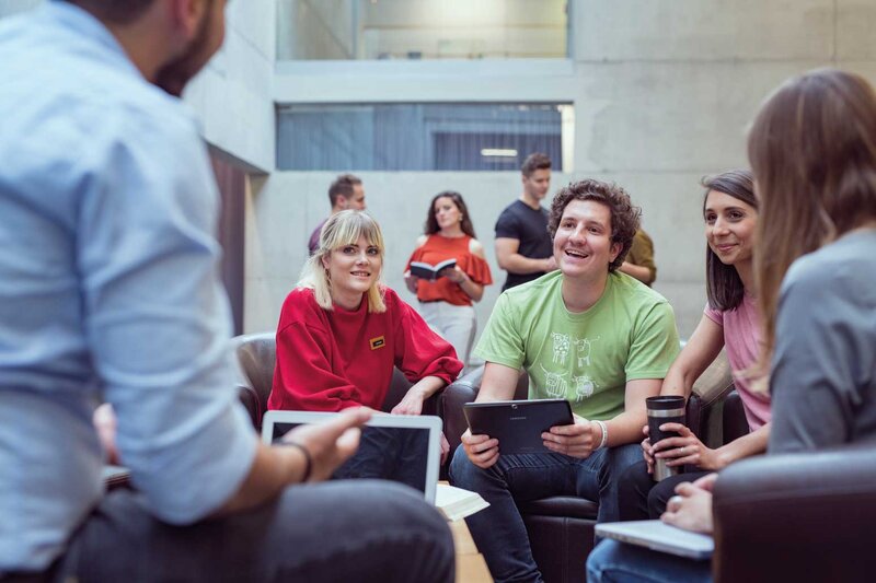Gruppe von Studierenden der HOK arbeitet gemeinsam an einem Projekt in der Aula der Hochschule.
