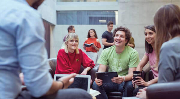 Gruppe von Studierenden der HOK arbeitet gemeinsam an einem Projekt in der Aula der Hochschule.