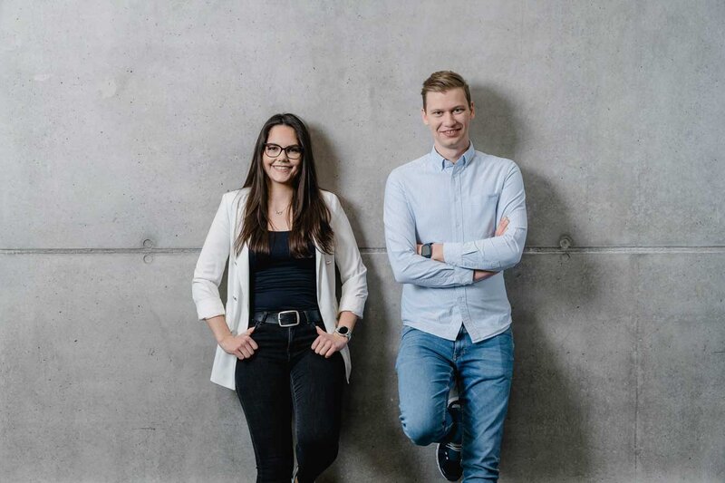 Zwei Studierende der HOK vor einer Betonwand – Portrait im modernen Campusstil.