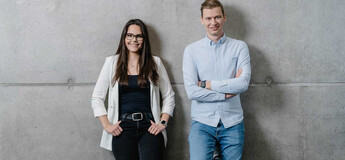 Zwei Studierende der HOK vor einer Betonwand – Portrait im modernen Campusstil.