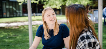 Zwei Studierende der HOK im Gespräch auf dem Campusgelände an einem sonnigen Tag.